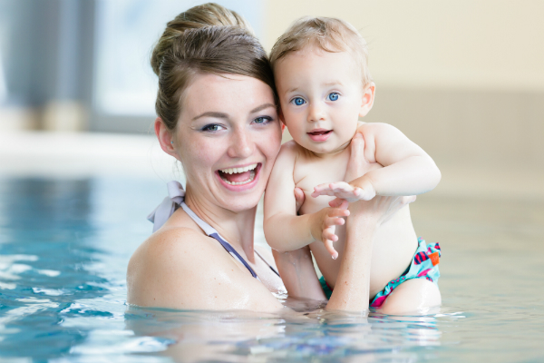 Mutter mit neugeborenem Kind beim Babyschwimmen