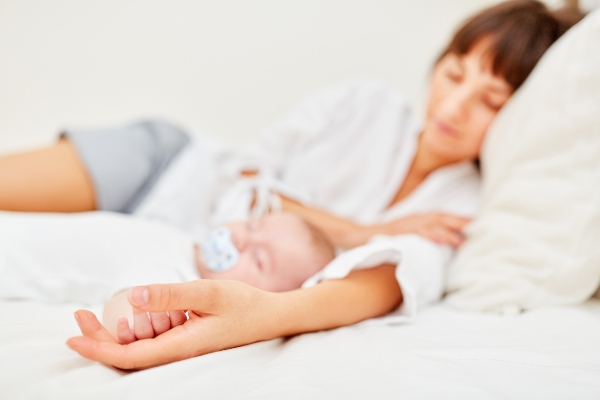 Mutter und neugeborenes Baby halten friedlich Mittagsschlaf Hand in Hand