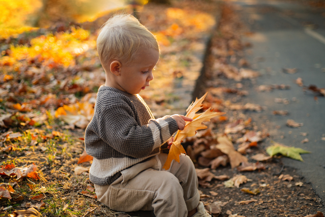 Kind spielt mit großem Laubblatt
